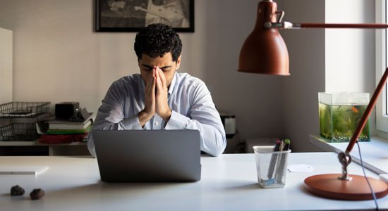 Um rapaz em frente ao computador preocupado.